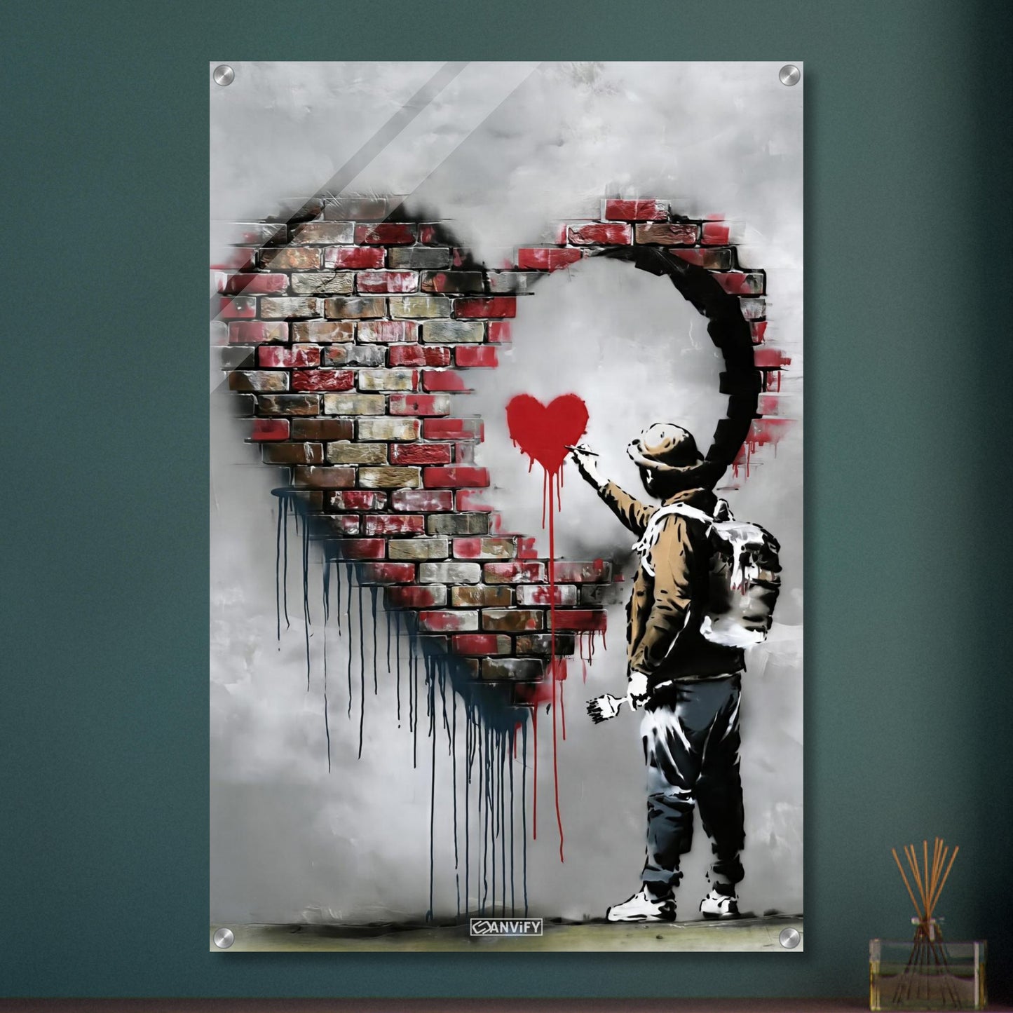 Künstler malt ein kleines rotes Herz in einem großen Herz aus Ziegelsteinen im Banksy Stil auf einem Acrylbild