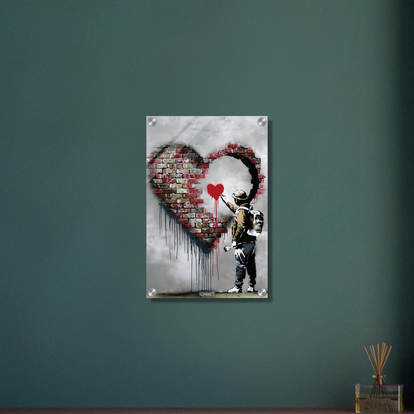 Künstler malt ein kleines rotes Herz in einem großen Herz aus Ziegelsteinen im Banksy Stil auf einem Acrylbild