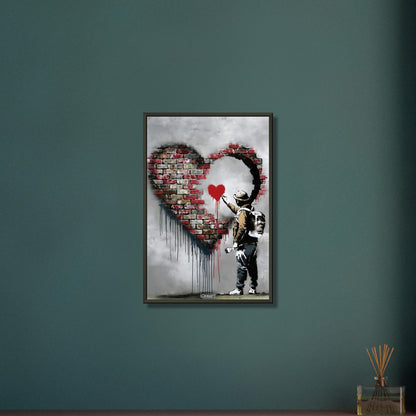 Künstler malt ein kleines rotes Herz in einem großen Herz aus Ziegelsteinen im Banksy Stil auf einem Poster im Metallrahmen
