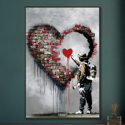 Künstler malt ein kleines rotes Herz in einem großen Herz aus Ziegelsteinen im Banksy Stil auf einem Poster im Metallrahmen