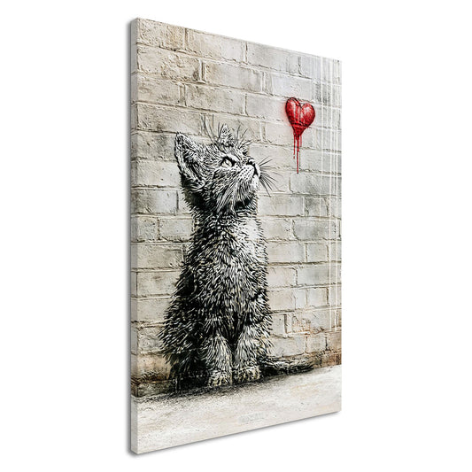 Kleine Katze im Banksy Stil blickt auf ein rotes Herz hoch auf einer Leinwand