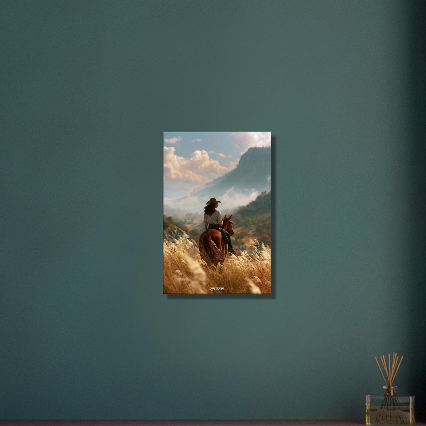 Cowgirl auf einem braunen Pferd im Weizenfeld vor einer Berglandschaft auf einer Leinwand
