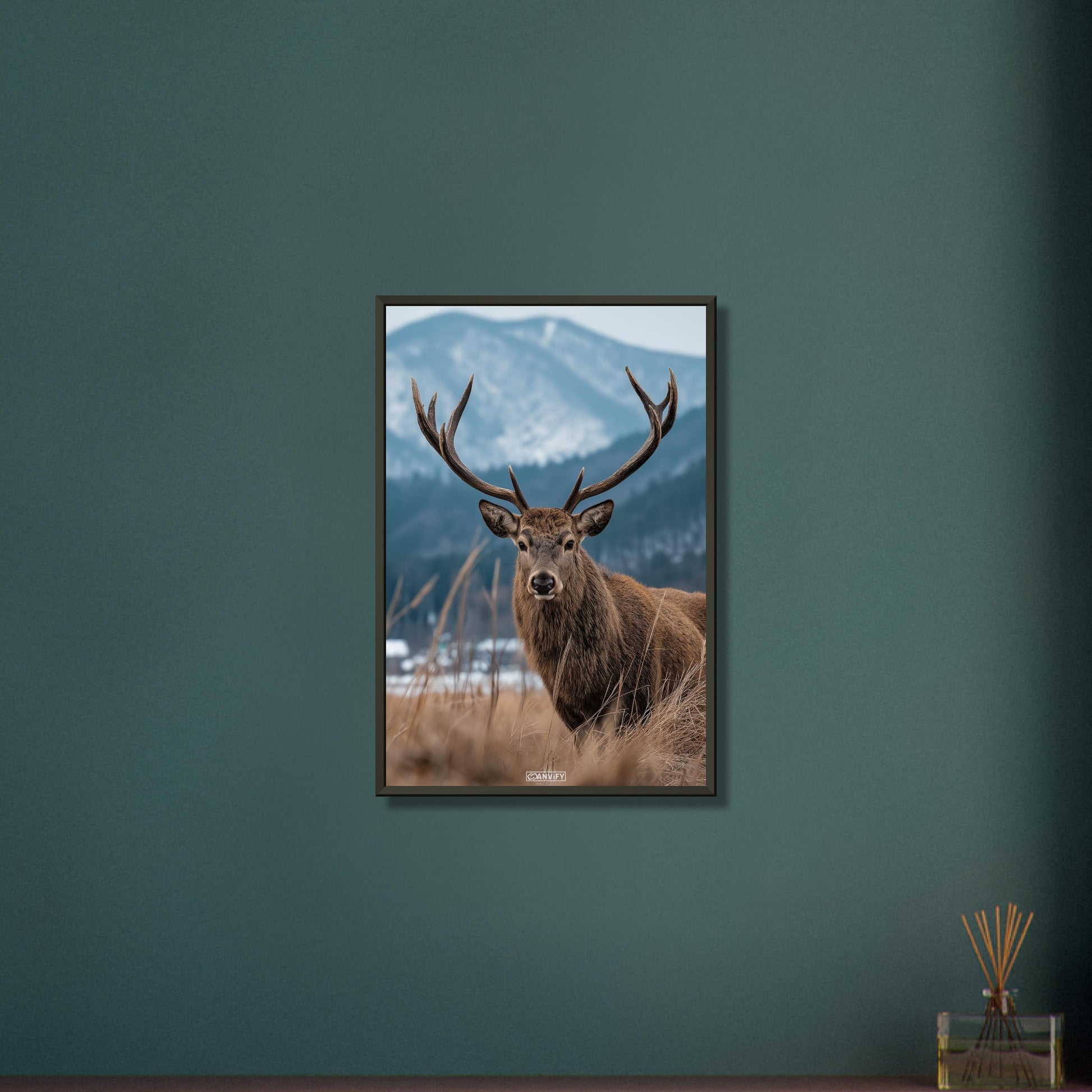 Hirsch mit großem Geweih am offenen Feld neben einem Nadelwald auf einem Poster im Metallrahmen