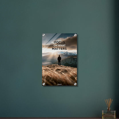 Mann steht auf der Klippe mit dem Rücken zur Kamera und blickt auf den Sonnenaufgang mit dem Motivationsspruch "Focus On What Matters" auf einem Acrylbild