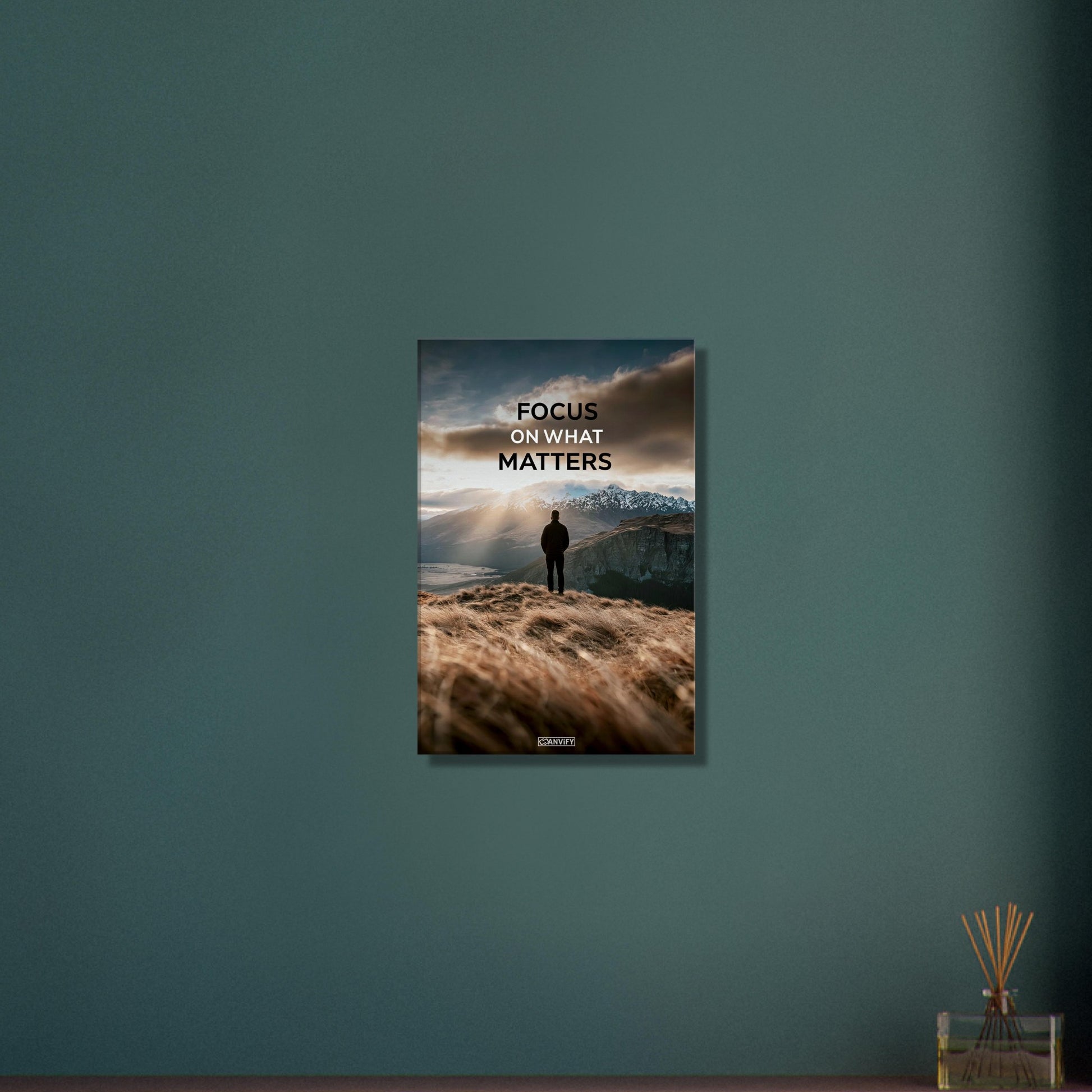 Mann steht auf der Klippe mit dem Rücken zur Kamera und blickt auf den Sonnenaufgang mit dem Motivationsspruch "Focus On What Matters" auf einer Leinwand