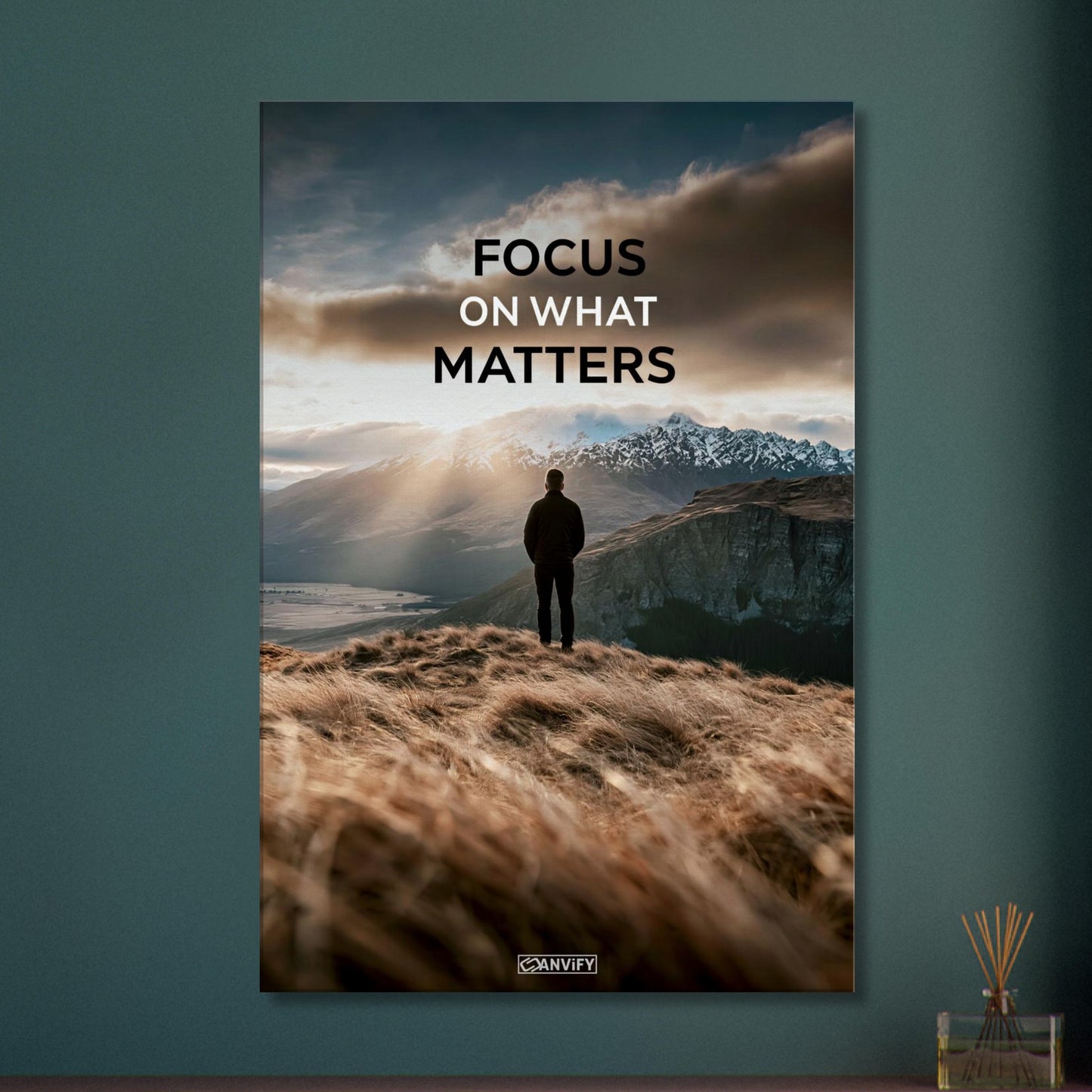Mann steht auf der Klippe mit dem Rücken zur Kamera und blickt auf den Sonnenaufgang mit dem Motivationsspruch "Focus On What Matters" auf einer Leinwand
