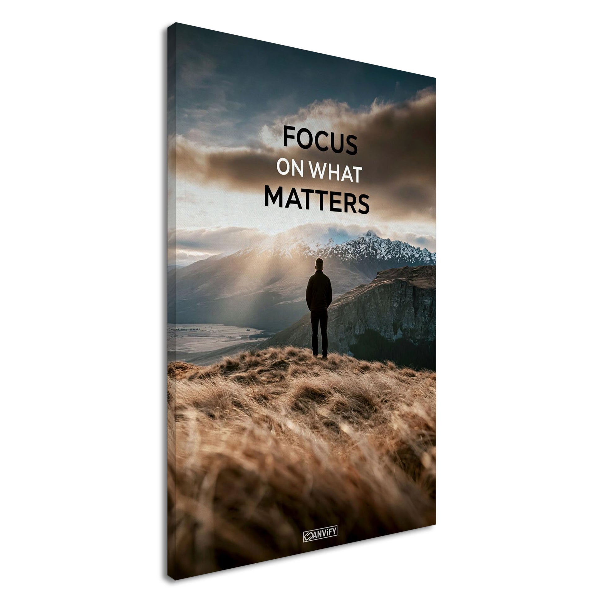Mann steht auf der Klippe mit dem Rücken zur Kamera und blickt auf den Sonnenaufgang mit dem Motivationsspruch "Focus On What Matters" auf einer Leinwand