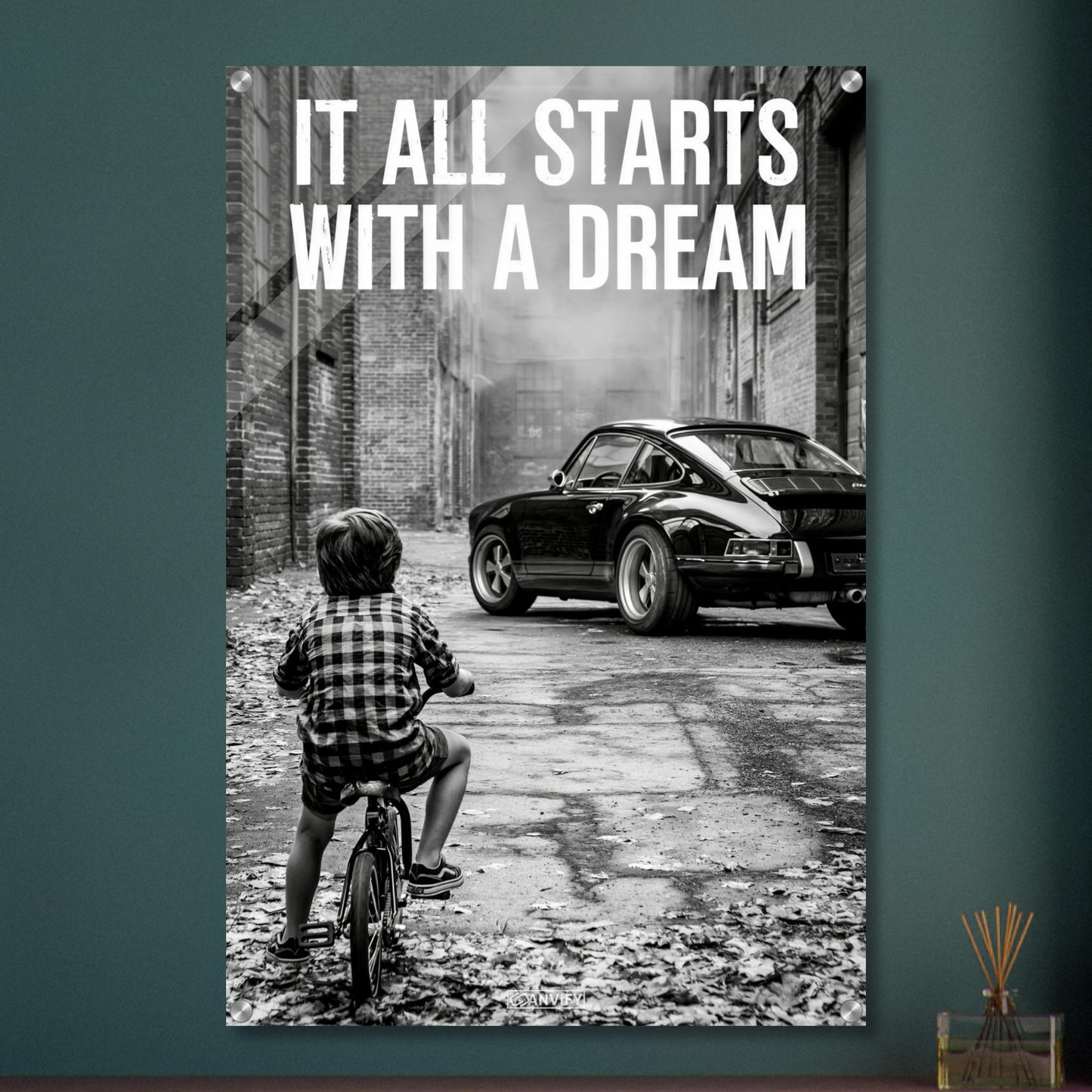 Kleiner Junge auf dem Fahrrad blickt auf einen Porsche 911 mit dem Motivationsspruch "It All Starts With A Dream" auf einem Acrylbild