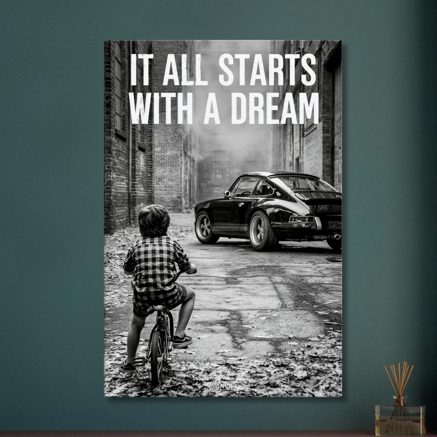 Kleiner Junge auf dem Fahrrad blickt auf einen Porsche 911 mit dem Motivationsspruch "It All Starts With A Dream" auf einer Leinwand