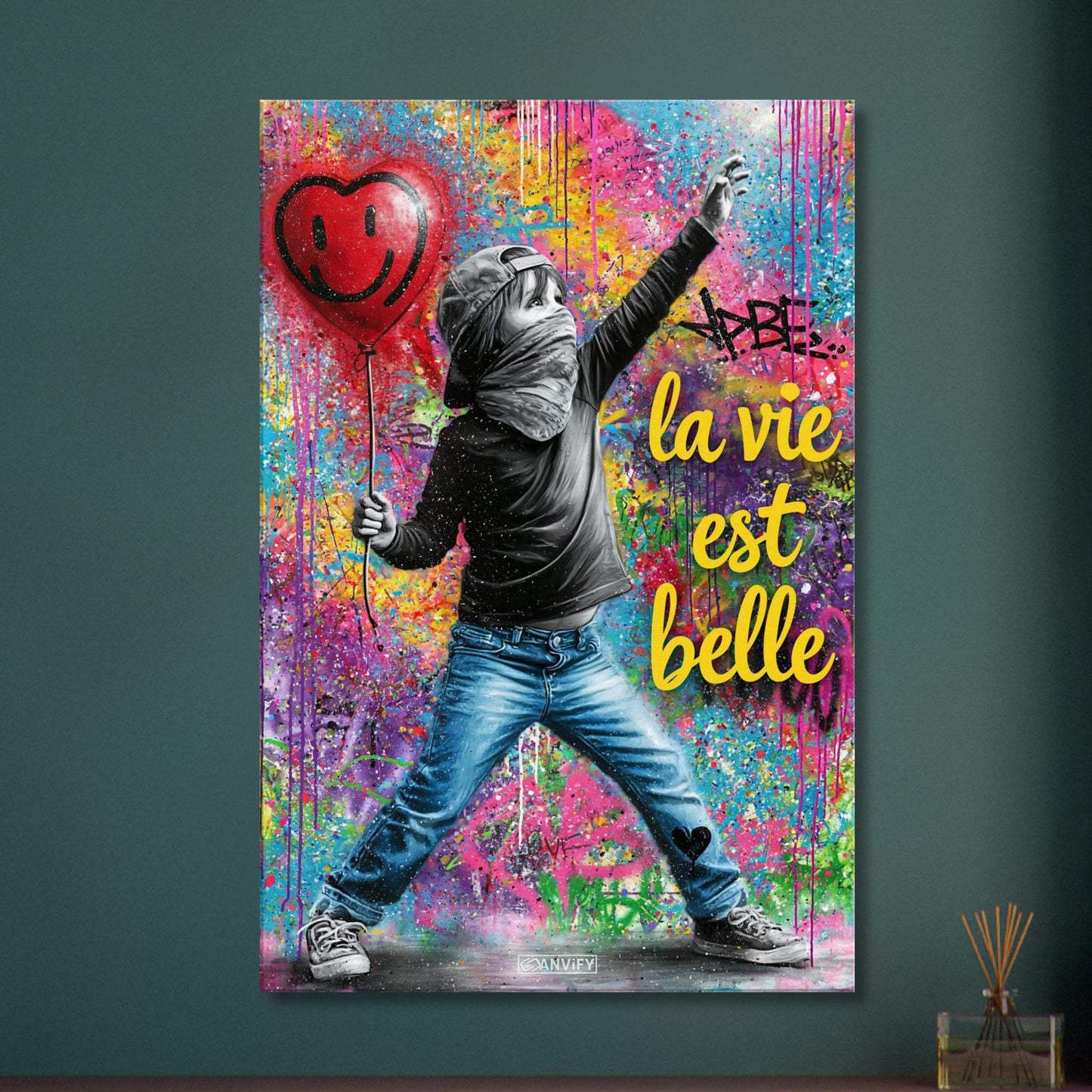 Kleiner Junge mit Basecap, Bandana und einem Herzluftballon in der Hand und einem Spruch "La Vie Est Belle" im Pop Art Stil auf einer Leinwand