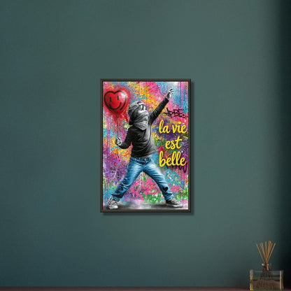 Kleiner Junge mit Basecap, Bandana und einem Herzluftballon in der Hand und einem Spruch "La Vie Est Belle" im Pop Art Stil auf einem Poster im Metallrahmen