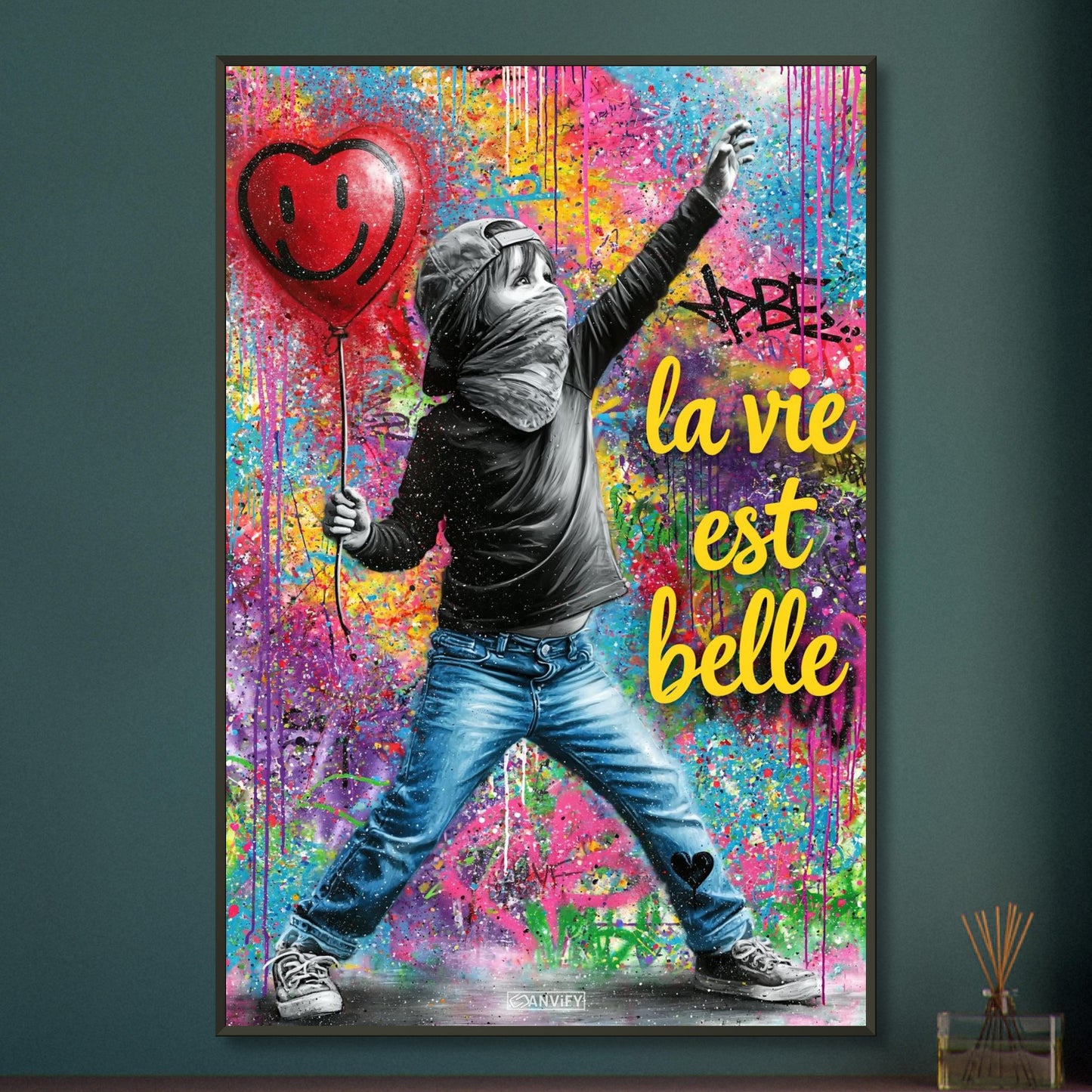 Kleiner Junge mit Basecap, Bandana und einem Herzluftballon in der Hand und einem Spruch "La Vie Est Belle" im Pop Art Stil auf einem Poster im Metallrahmen