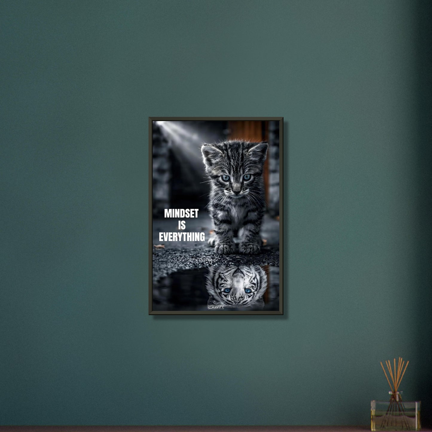 Katzenbaby blickt in eine Wasserpfütze und sieht sich darin als einen großen Tiger mit einem Motivationsspruch "Mindset Is Everything" auf einem Poster im Metallrahmen