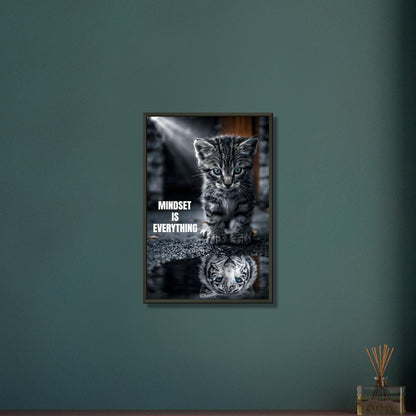 Katzenbaby blickt in eine Wasserpfütze und sieht sich darin als einen großen Tiger mit einem Motivationsspruch "Mindset Is Everything" auf einem Poster im Metallrahmen