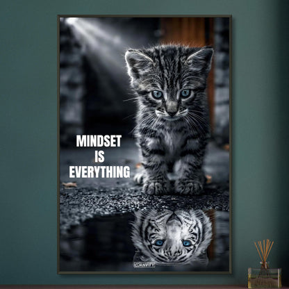 Katzenbaby blickt in eine Wasserpfütze und sieht sich darin als einen großen Tiger mit einem Motivationsspruch "Mindset Is Everything" auf einem Poster im Metallrahmen