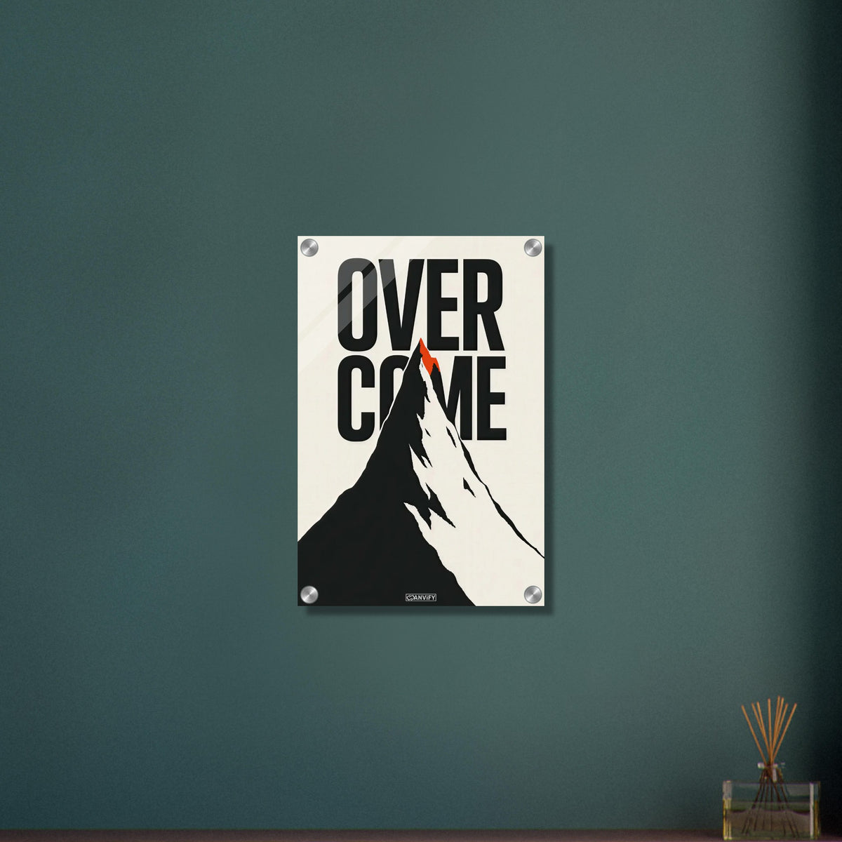 Minimalistisch gezeichneter Berg in Schwarz und Weiß mit einem Spruch 'Overcome' und mit einer roten Bergspitze auf einem Acrylbild