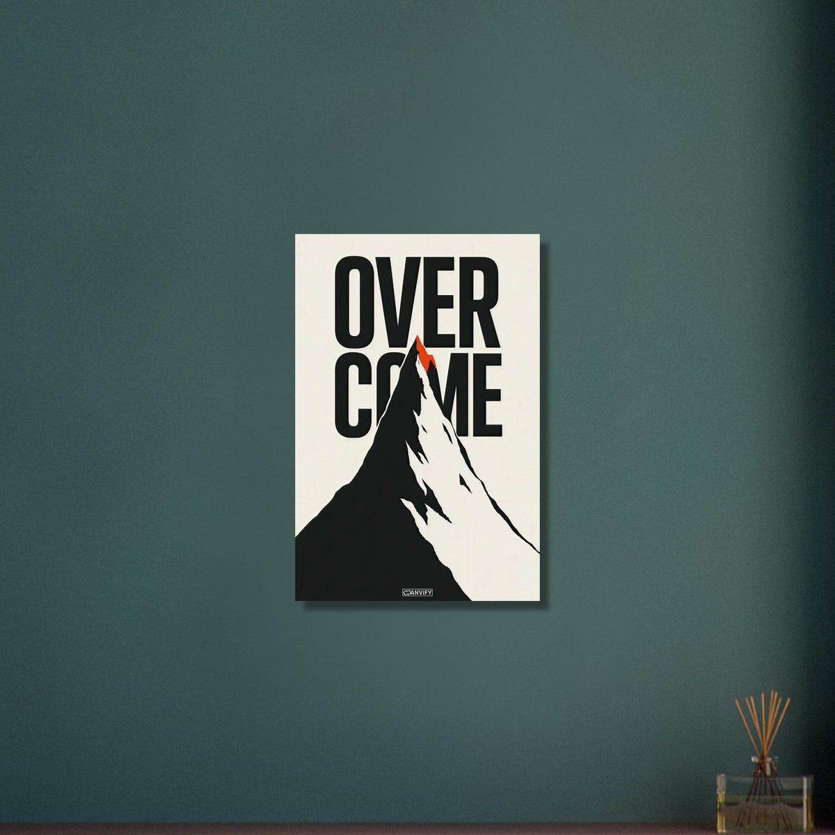 Minimalistisch gezeichneter Berg in Schwarz und Weiß mit einem Spruch 'Overcome' und mit einer roten Bergspitze auf Aluminium