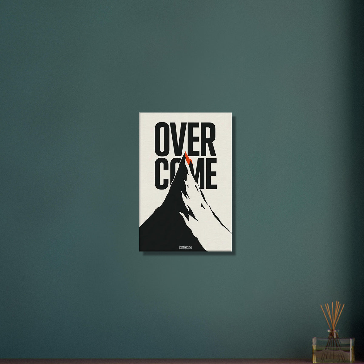 Minimalistisch gezeichneter Berg in Schwarz und Weiß mit einem Spruch 'Overcome' und mit einer roten Bergspitze auf einer Leinwand