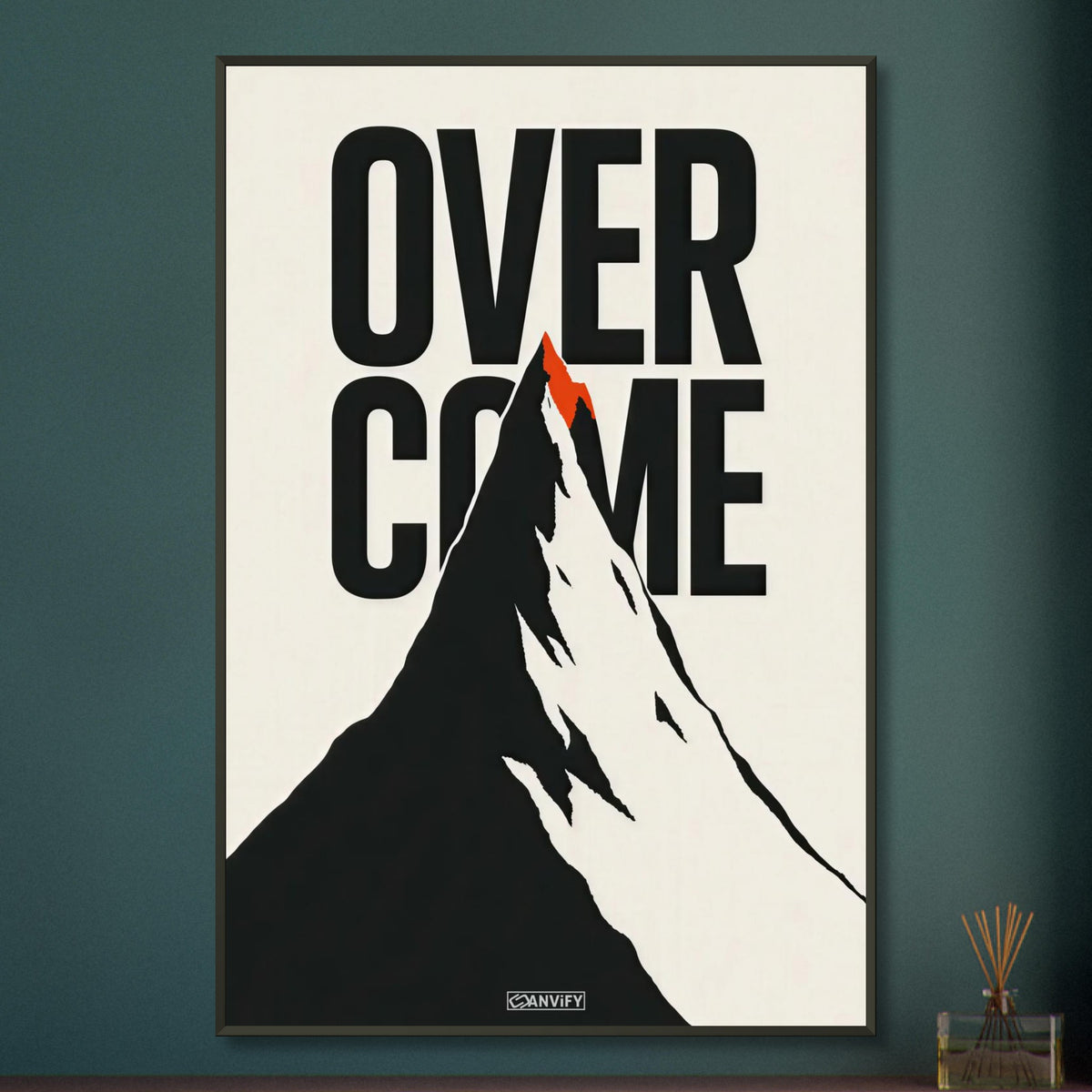 Minimalistisch gezeichneter Berg in Schwarz und Weiß mit einem Spruch 'Overcome' und mit einer roten Bergspitze auf einem Poster im Metallrahmen