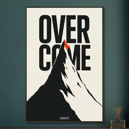 Minimalistisch gezeichneter Berg in Schwarz und Weiß mit einem Spruch 'Overcome' und mit einer roten Bergspitze auf einem Poster im Metallrahmen
