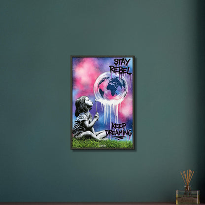 Mädchen pustet eine Seifenblase mit einer Weltkugel darin auf und mit Spruch 'Stay Rebel, Keep Dreaming' im Pop Art Stil auf einem Poster im Metallrahmen