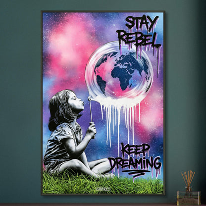 Mädchen pustet eine Seifenblase mit einer Weltkugel darin auf und mit Spruch 'Stay Rebel, Keep Dreaming' im Pop Art Stil auf einem Poster im Metallrahmen