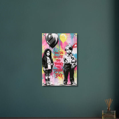 Junge mit einem Teddybär und ein Mädchen mit einem Luftballon in der Hand im Banksy Stil mit einem Spruch "You Are Never Too Young To Dream Big" auf einem Acrylbild