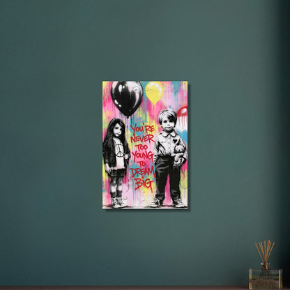 Junge mit einem Teddybär und ein Mädchen mit einem Luftballon in der Hand im Banksy Stil mit einem Spruch "You Are Never Too Young To Dream Big" auf Aluminium